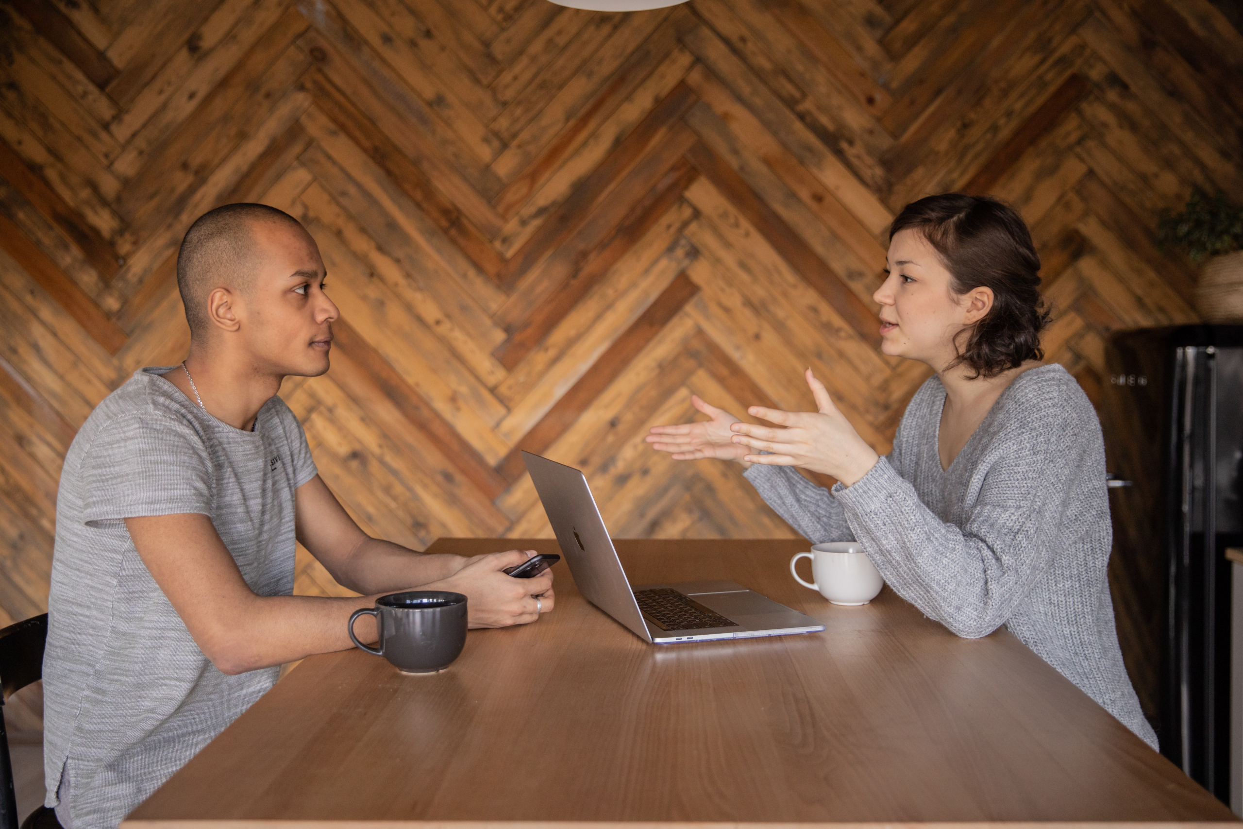 Woman from SEO agency sitting with a laptop in front of her describing a product on her business blog to a man